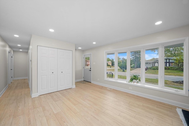 unfurnished bedroom with light wood-type flooring, a closet, and multiple windows