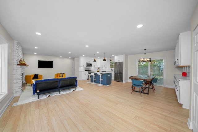 living room featuring a fireplace, a chandelier, and light hardwood / wood-style floors