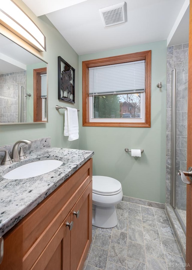 bathroom featuring vanity, a shower with door, and toilet