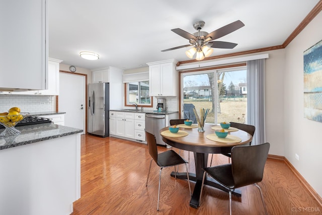 dining room with crown molding, ceiling fan, sink, and light wood-type flooring