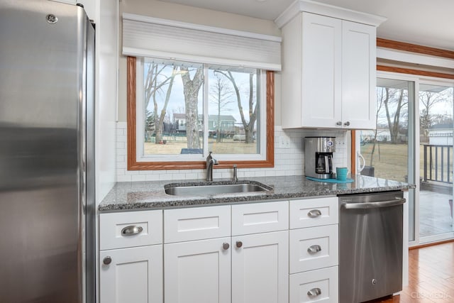 kitchen featuring sink, stainless steel appliances, dark stone counters, and white cabinets