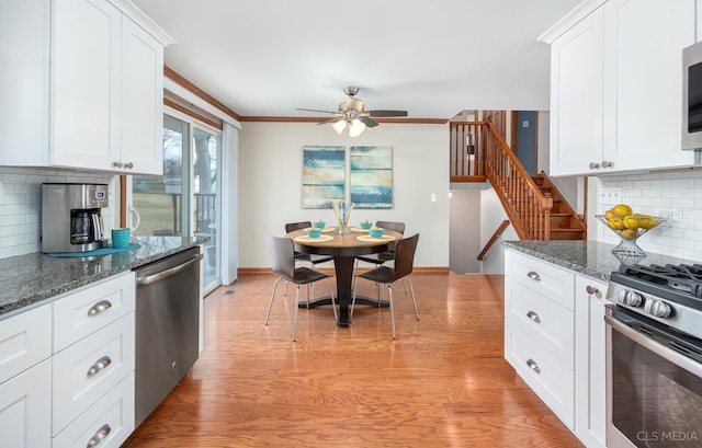 kitchen featuring ceiling fan, dark stone countertops, stainless steel appliances, white cabinets, and light wood-type flooring