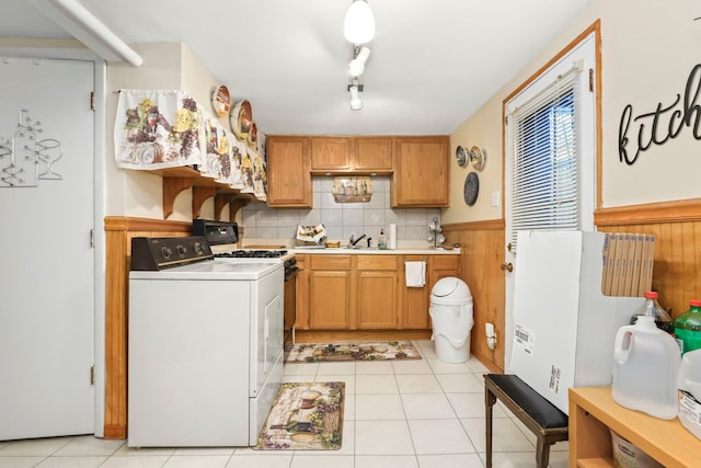 kitchen with light tile patterned flooring, sink, gas range gas stove, tasteful backsplash, and washer / clothes dryer