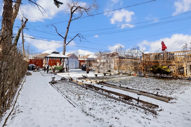 yard layered in snow with a gazebo and a deck