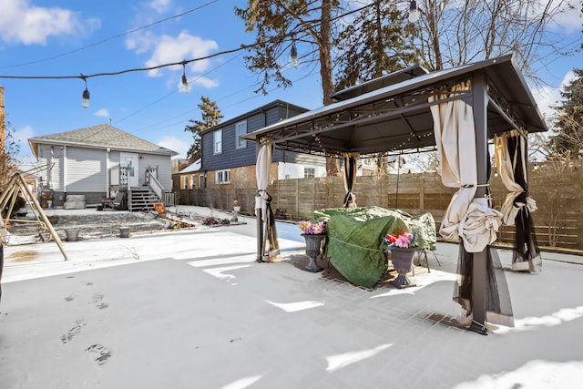 snow covered patio featuring a gazebo and an outbuilding