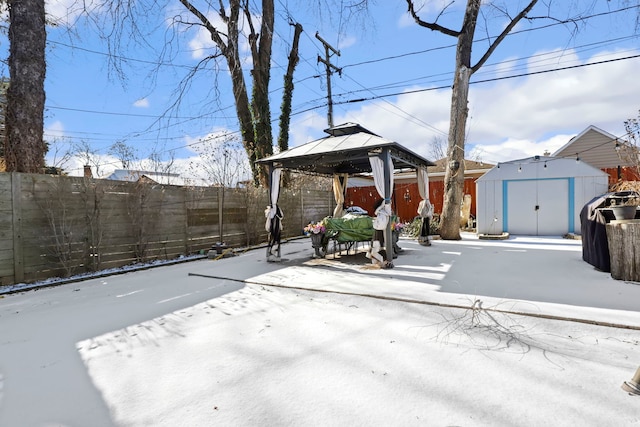 snow covered patio with a shed and a gazebo