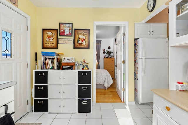 kitchen with light tile patterned floors, white cabinets, and white refrigerator