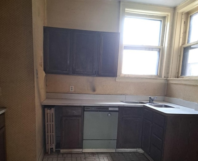 kitchen with light countertops, dishwasher, a sink, and wallpapered walls