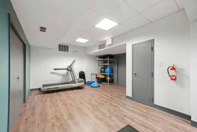 workout room with a drop ceiling and light hardwood / wood-style floors