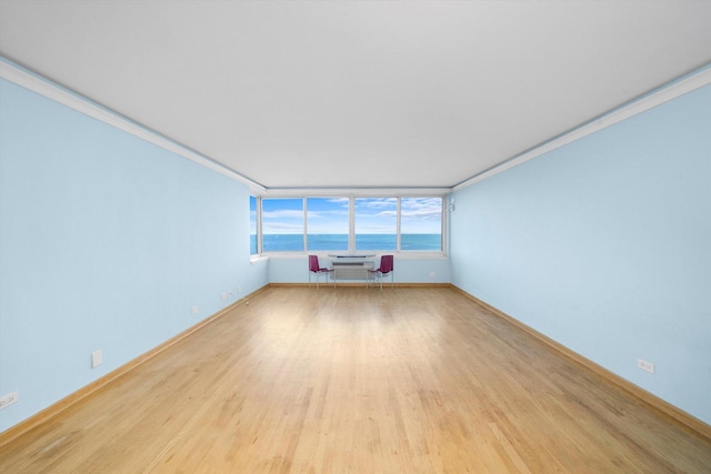 unfurnished living room featuring a wall mounted AC, crown molding, and light hardwood / wood-style flooring