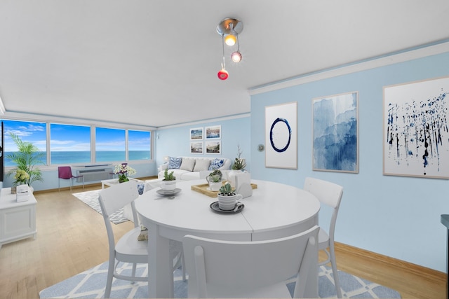 dining room with crown molding, a water view, and light hardwood / wood-style flooring