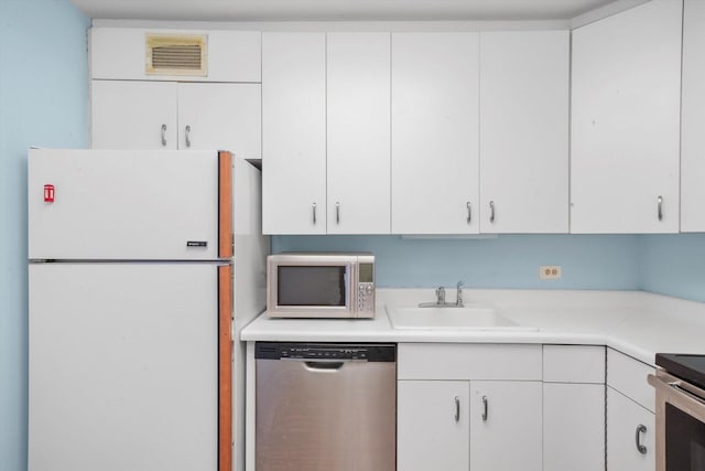 kitchen with stainless steel appliances, white cabinetry, and sink