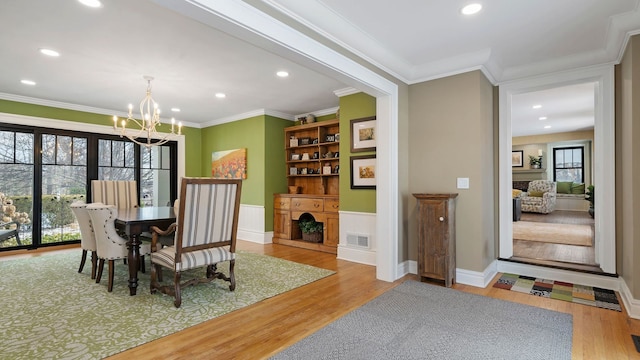 dining area featuring a wealth of natural light, crown molding, wood-type flooring, and a notable chandelier