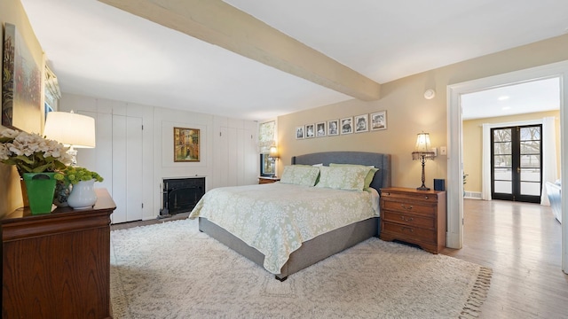 bedroom with hardwood / wood-style floors, beamed ceiling, and french doors