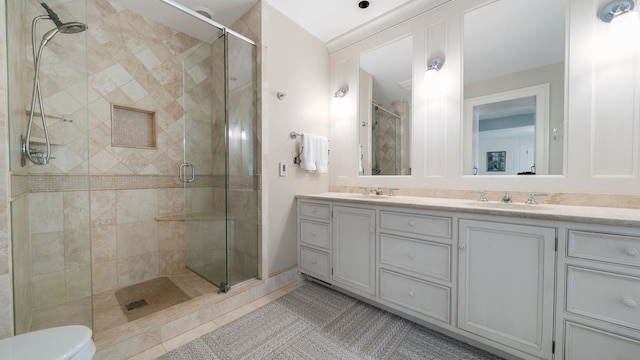 bathroom with a shower with shower door, toilet, vanity, and tile patterned flooring