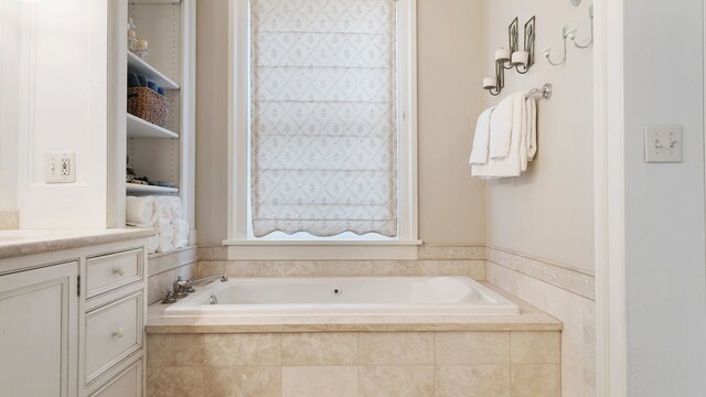 bathroom featuring vanity and tiled tub