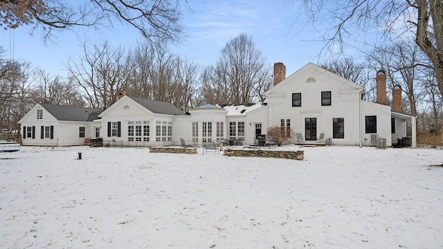 snow covered rear of property featuring cooling unit