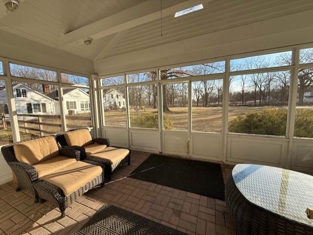 sunroom featuring lofted ceiling with beams