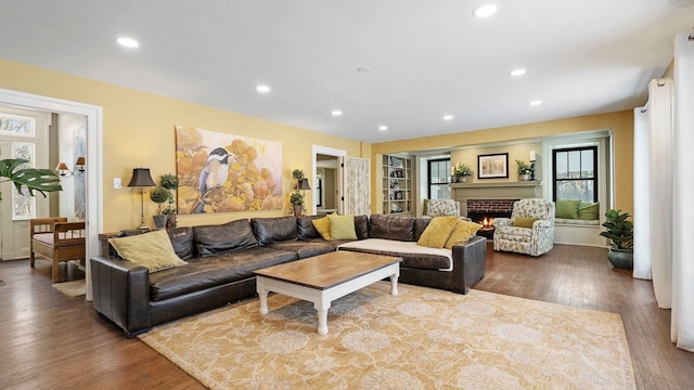 living room with a brick fireplace and hardwood / wood-style floors