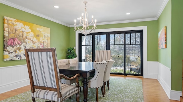 dining room with a notable chandelier, crown molding, and light hardwood / wood-style flooring