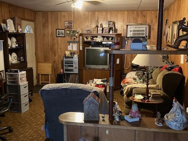 office space with ceiling fan, a wall mounted air conditioner, carpet floors, and wooden walls