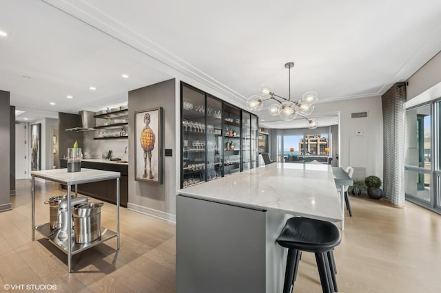 kitchen featuring light hardwood / wood-style floors, decorative light fixtures, wall chimney exhaust hood, and a kitchen island