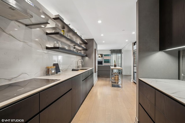 kitchen with sink, light wood-type flooring, light stone countertops, and decorative backsplash