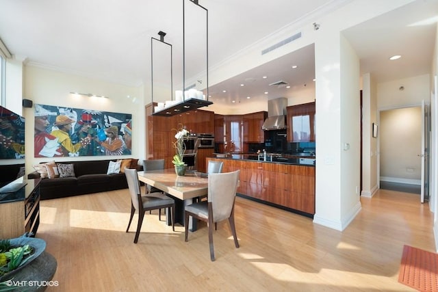 dining area featuring light wood-type flooring, ornamental molding, and sink