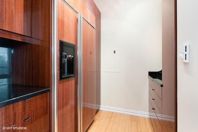 kitchen featuring light wood-type flooring, electric panel, and paneled refrigerator