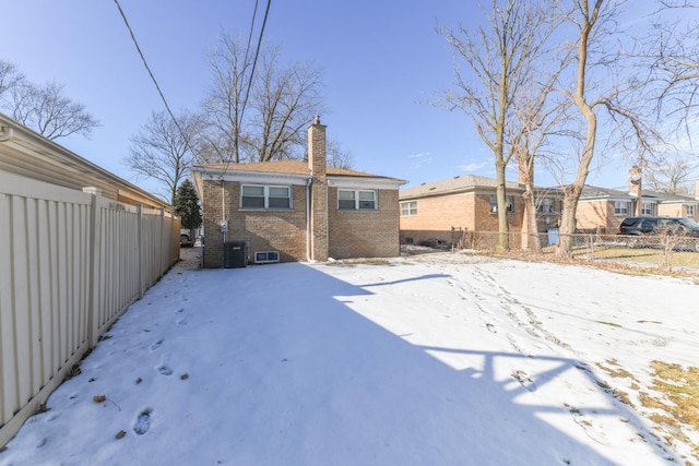 snow covered back of property featuring central air condition unit