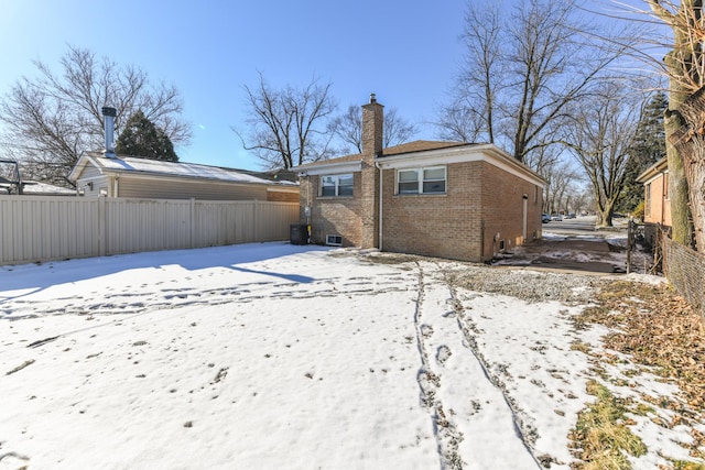 snow covered rear of property with central AC