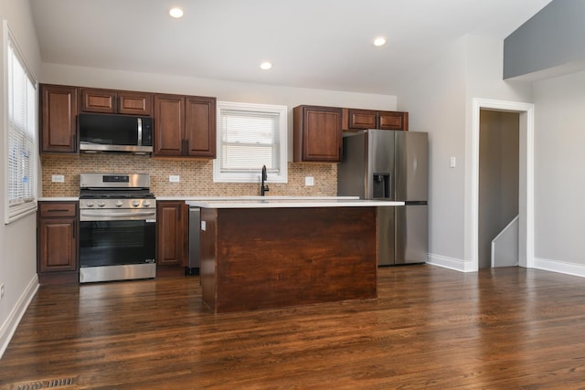 kitchen with stainless steel appliances, decorative backsplash, dark hardwood / wood-style flooring, and a kitchen island