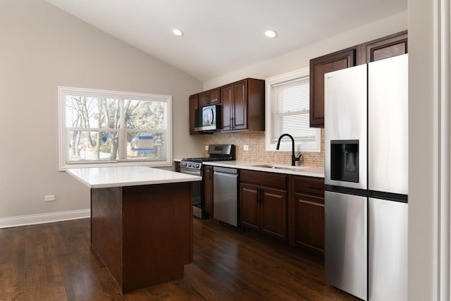 kitchen featuring lofted ceiling, a center island, sink, dark wood-type flooring, and stainless steel appliances