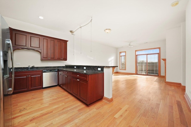 kitchen featuring kitchen peninsula, ceiling fan, light wood-type flooring, hanging light fixtures, and stainless steel dishwasher