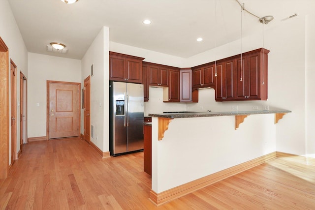 kitchen with stainless steel refrigerator with ice dispenser, a kitchen breakfast bar, hanging light fixtures, and kitchen peninsula