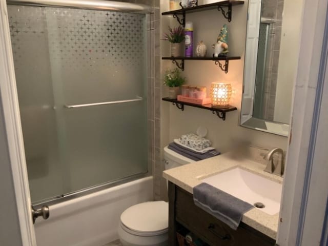 full bathroom with toilet, shower / bath combination with glass door, and vanity