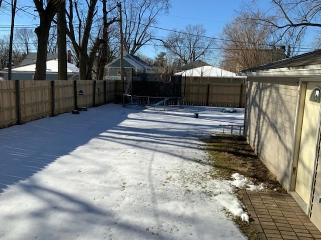 yard layered in snow with a trampoline