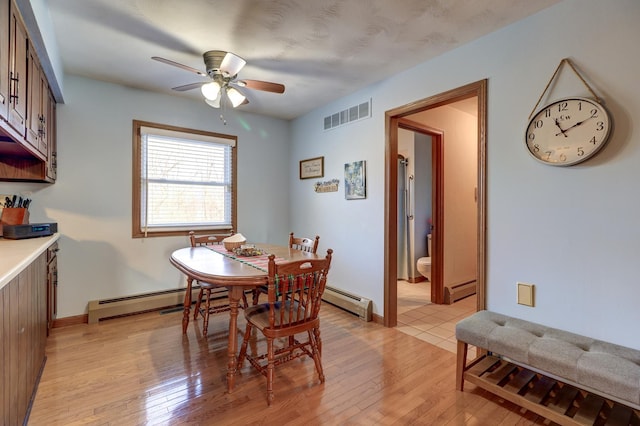 dining space with a baseboard radiator, ceiling fan, and light hardwood / wood-style flooring