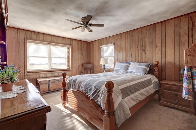 bedroom featuring ceiling fan, light carpet, and wooden walls