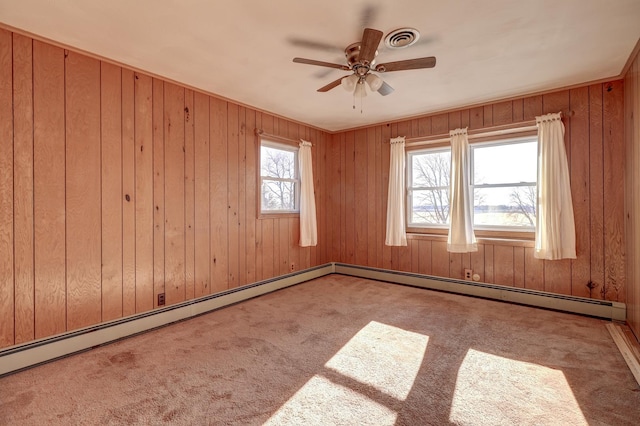 empty room featuring ceiling fan, light colored carpet, and wood walls