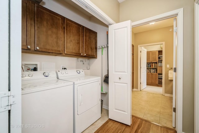 laundry area with cabinets, washer and clothes dryer, and light hardwood / wood-style flooring