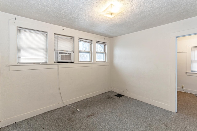 empty room with cooling unit, carpet, and a textured ceiling