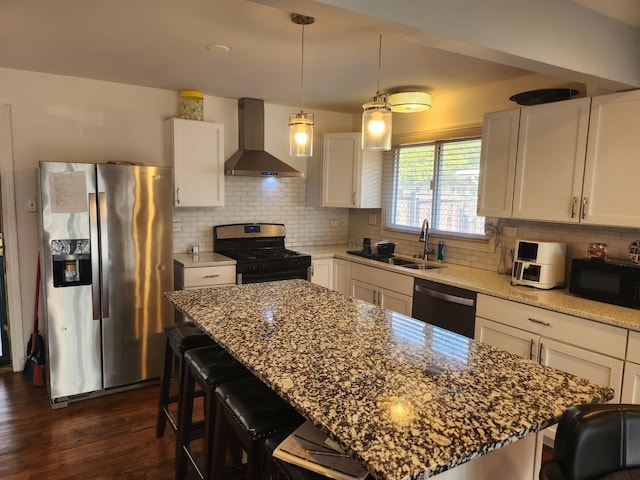 kitchen featuring black appliances, wall chimney range hood, white cabinetry, and a center island