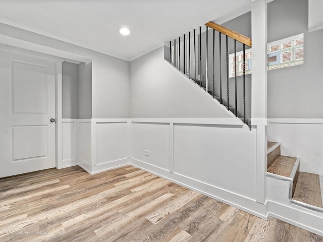 spare room featuring stairway, wainscoting, a decorative wall, and wood finished floors