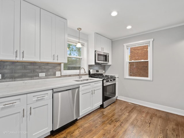 kitchen with baseboards, a sink, appliances with stainless steel finishes, white cabinetry, and tasteful backsplash