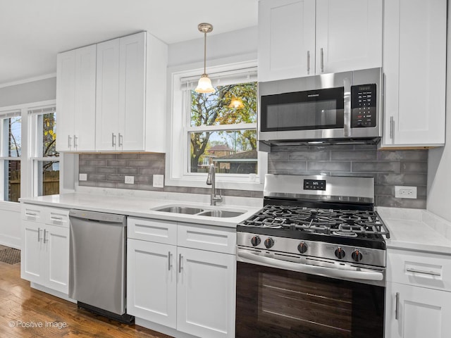 kitchen with a sink, appliances with stainless steel finishes, white cabinets, light countertops, and a healthy amount of sunlight