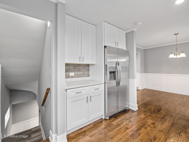 kitchen with crown molding, stainless steel fridge with ice dispenser, light countertops, white cabinets, and dark wood-style flooring