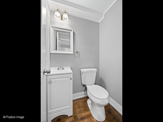 bathroom with crown molding, baseboards, toilet, wood finished floors, and vanity