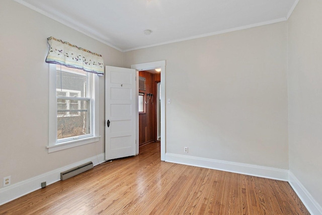 empty room featuring crown molding, light hardwood / wood-style flooring, and a baseboard radiator