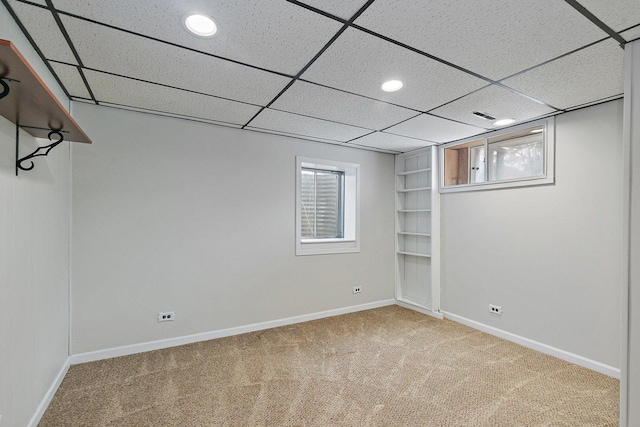 basement with a paneled ceiling and carpet flooring